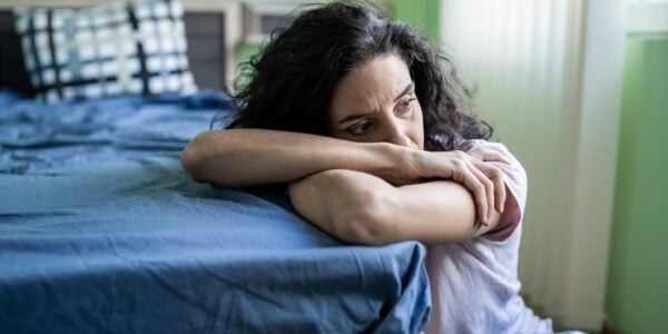 Worried woman alone in a room, resting her head on her arms