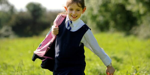 Happy girl runs home from school in her uniform