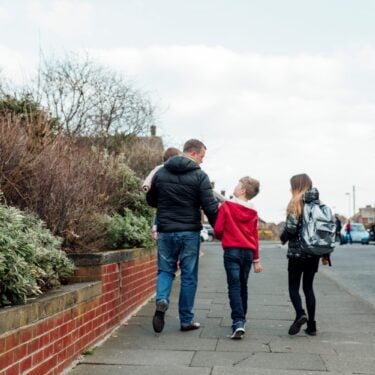 Dad holding baby walking with two kids