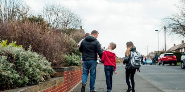 Dad holding baby walking with two kids