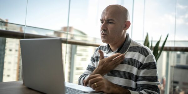 Man working on a laptop using sign language on a video call
