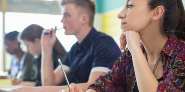 Teenage sixth form students taking notes in a lesson