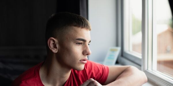 Teenage boy looking out of window
