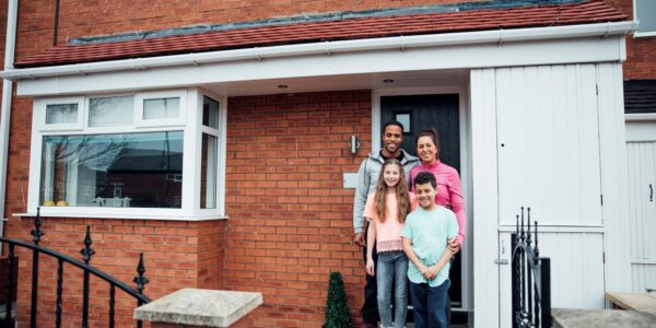 Mother, father, son and daughter standing in front of their house