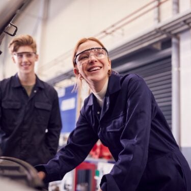 Male and female apprentices looking at car engine