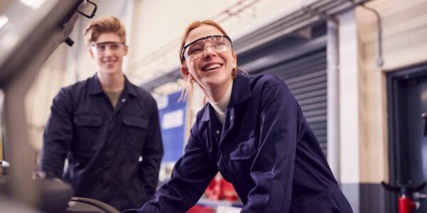 Male and female apprentices looking at car engine