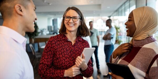 Three colleagues smiling and talking at work