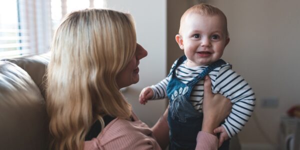 Happy mother and happy baby boy at home playing on the sof