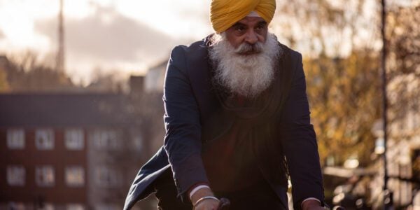 Older Sikh man cycling on bike in early morning