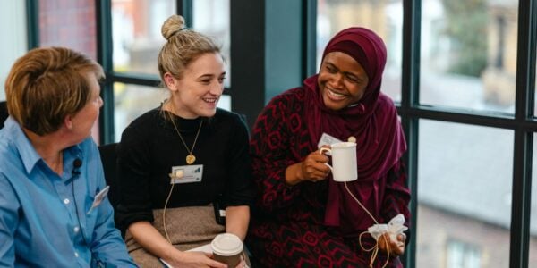 Catherine Dennison, Imogen Lambert and Aisha Abubakar chatting and smiling over cups of coffee at the early career researcher event