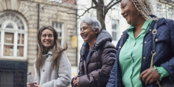 three women walking along street laughing and smiling
