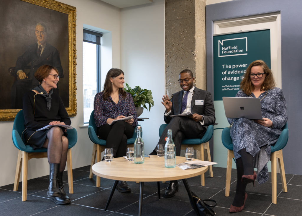 Final panel are seated on stage. The backdrop is a branded banenr, a white wall and the edge of a gold-framed painting. From left to right: Dame Clare Tickell (Nuffield Foundation Trustee and panel chair) Polly Curtis (CEO, Demos)
Andrew Powell (Barrister, NFJO board member)
Fiona Rutherford (CEO, JUSTICE)