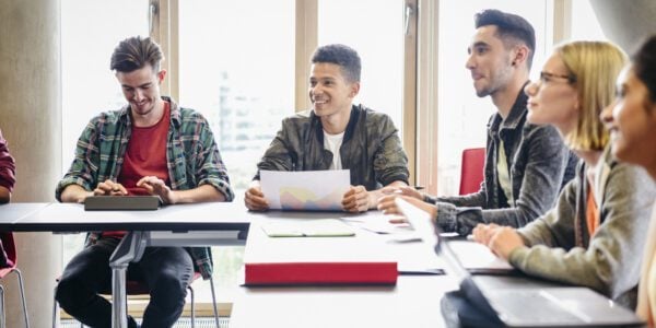 Group of students sit around a table listening.