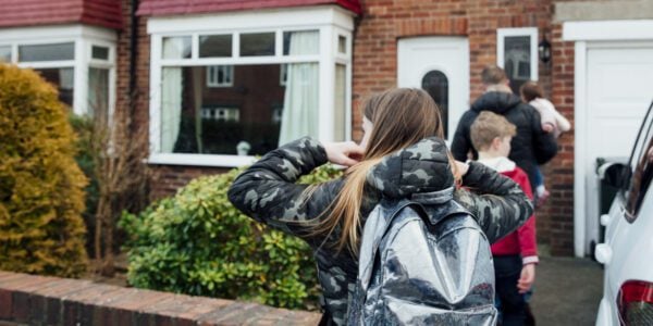 Dad and children are walking up to the front door of a house.