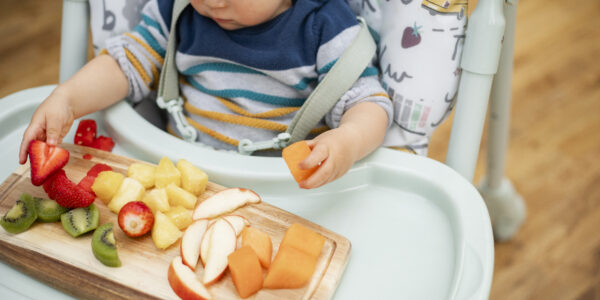 baby eating fruit on highchair