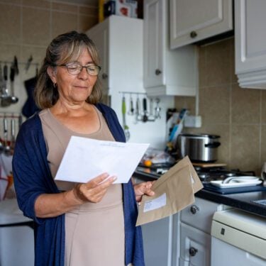 Portrait of a senior woman at home checking a letter in the mail