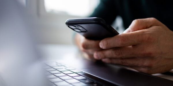 A medium close-up of a group of school children in red, white and black uniforms running in the school yard as they head to playtime.