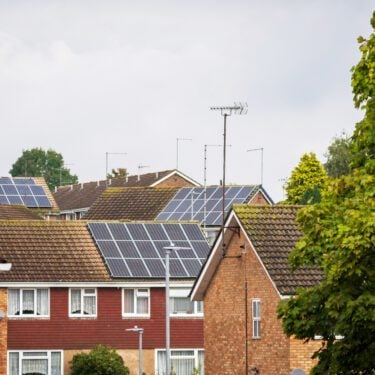 traditional detached house within residential estate in England UK, several houses in view have solar panels on the roof.