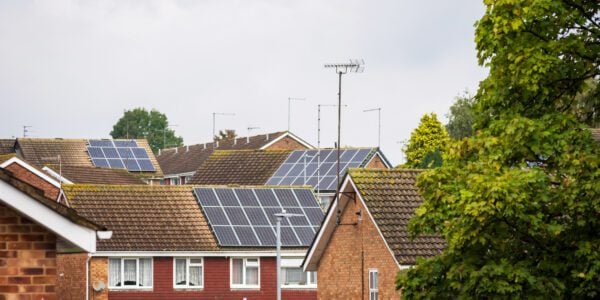 traditional detached house within residential estate in England UK, several houses in view have solar panels on the roof.
