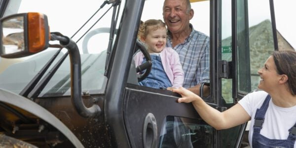 A shot of a grandfather sitting in a tractor with his young granddaughter, he is at his farm in North East, England. The grandfather and the girl's mother are teaching her about the farm.