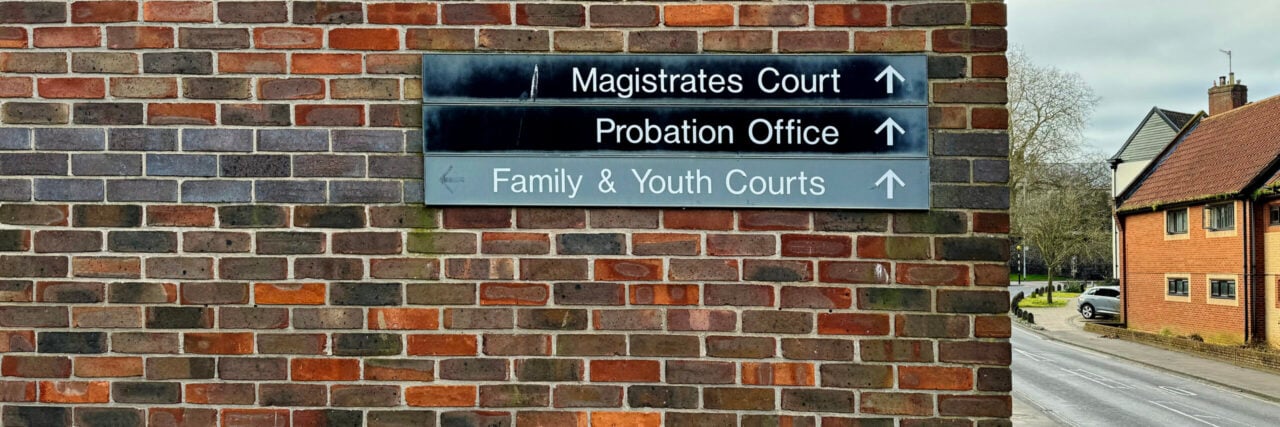 Directional signs to the courts in Norwich on the brick wall of a house
