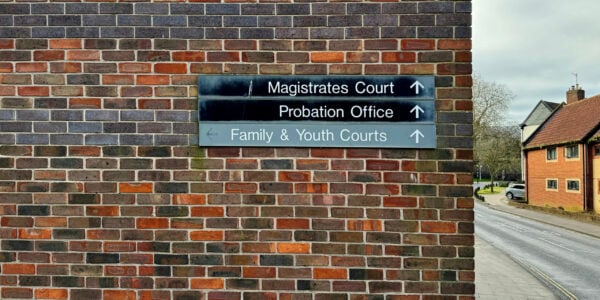 Directional signs to the courts in Norwich on the brick wall of a house