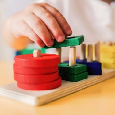 Kid playing with wood toys at pre school classroom.