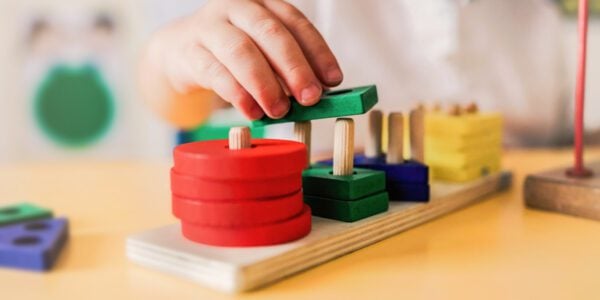 Kid playing with wood toys at pre school classroom.