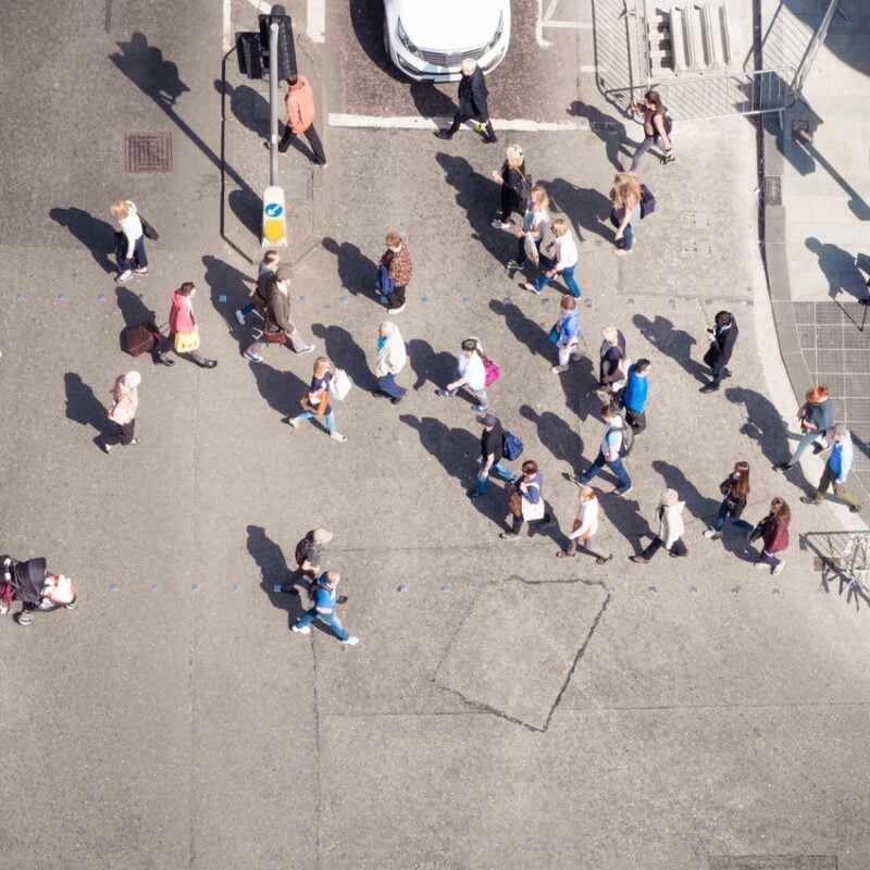 Pedestrians crossing a major city street in both directions, in Edinburgh, Scotland.